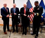 IMAGE: DAHLGREN, Va. (Feb. 22, 2018) – Capt. Godfrey 'Gus' Weekes, right, Naval Surface Warfare Center Dahlgren Division commanding officer, and Donald McCormack, left, executive director of the Naval Surface and Undersea Warfare Centers, present commemorative plaques to retired Adm. James Hogg, second from left, and Dr. Hans Mark, during an electromagnetic railgun line naming ceremony. As public servants, Hogg and Mark laid the foundation for the U.S. Navy Railgun Program and led the effort to explore and illustrate to senior leadership the warfighting advantages of this game-changing technology and were pivotal in gaining the initial funding necessary to demonstrate its feasibility. (U.S. Navy photo by John F. Williams/Released)