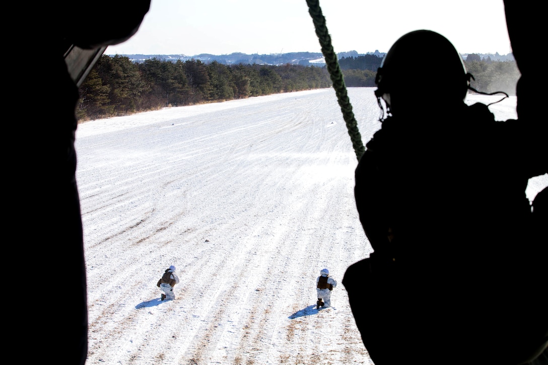 Marines set up a perimeter security while team members fast-rope from a V-22 Osprey aircraft while participating in vertical insertion during Exercise Forest Light