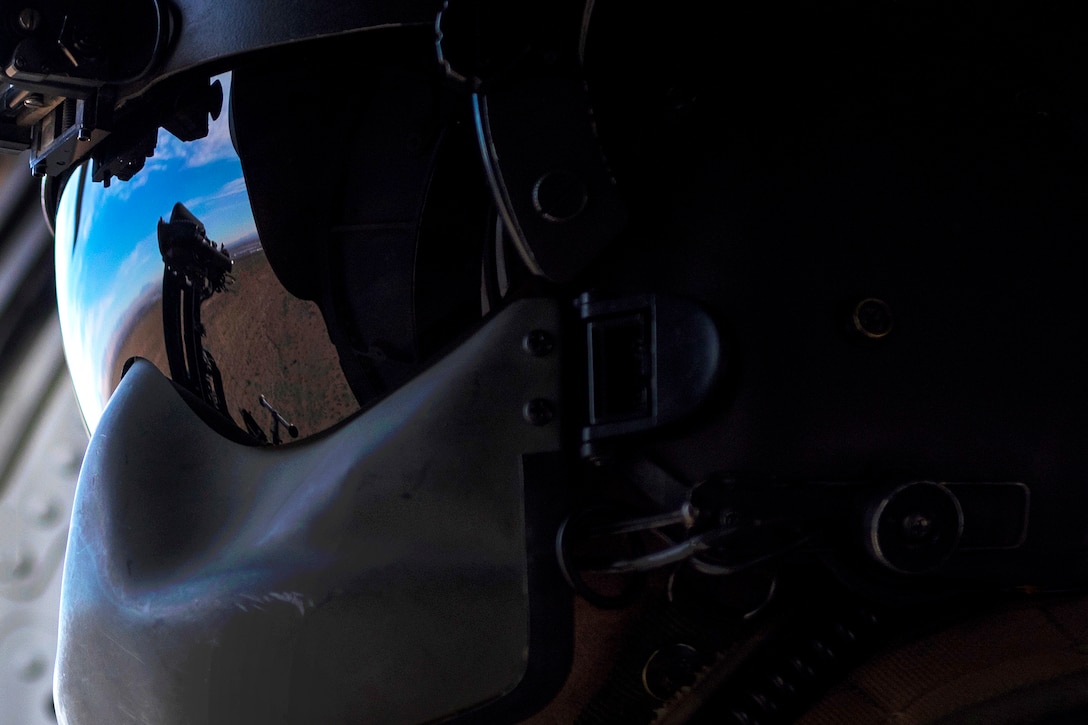 An airman looks out the side window of an HH-60G Pave Hawk helicopter during personnel recovery training.