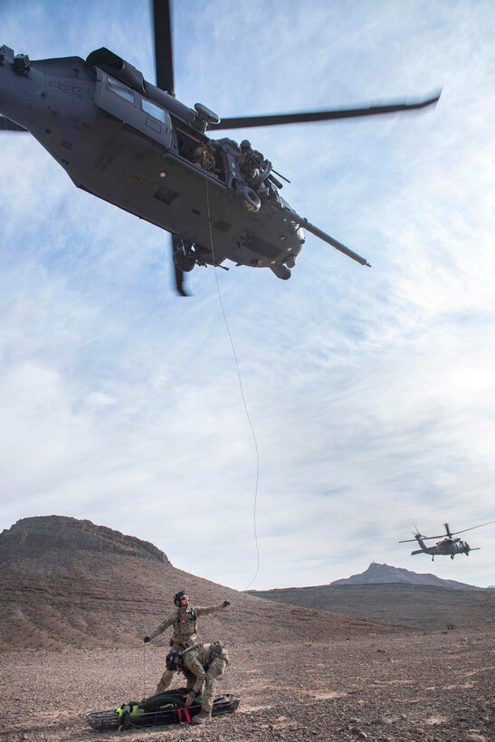Pararescuemen prepare to hoist a litter full of equipment into an HH-60G Pave Hawk helicopter during personnel recovery training.