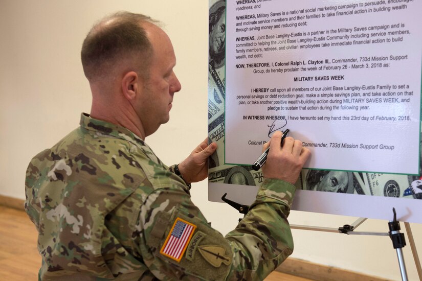 U.S. Army Col. Ralph L. Clayton III, 733rd Mission Support Group commander signs the Military Saves Week Proclamation at Fort Eustis' Lakeside Sports Bar at Joint Base Langley-Eustis, Virginia, Feb. 23, 2018. Clayton signed the proclamation as a show of support for educating service members and their families on the importance of financial management. (U.S. Air Force photo by Airman 1st Class Monica Roybal)