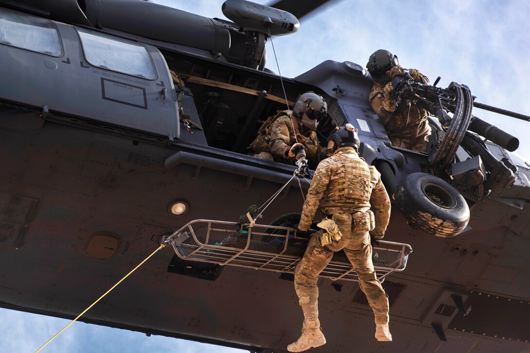 A pararescueman is hoisted into an HH-60G Pave Hawk helicopter during personnel recovery training.