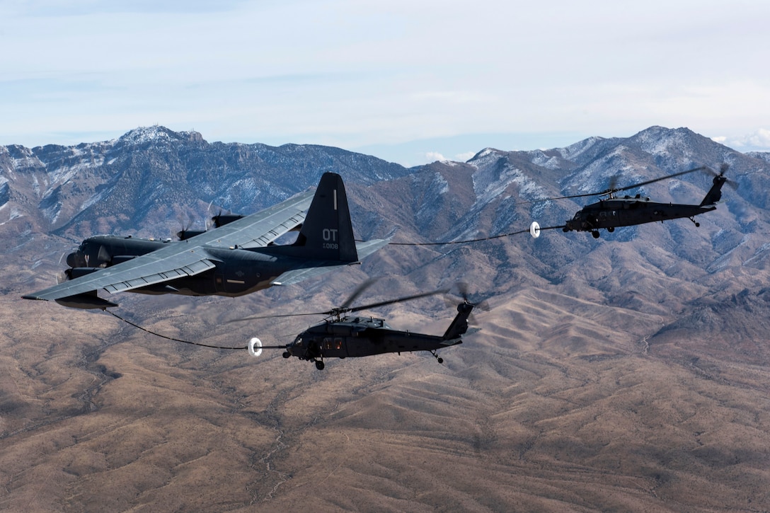 Two HH-60 Pave Hawk helicopters receive fuel from a HC-130J Combat King II cargo aircraft during a training mission.