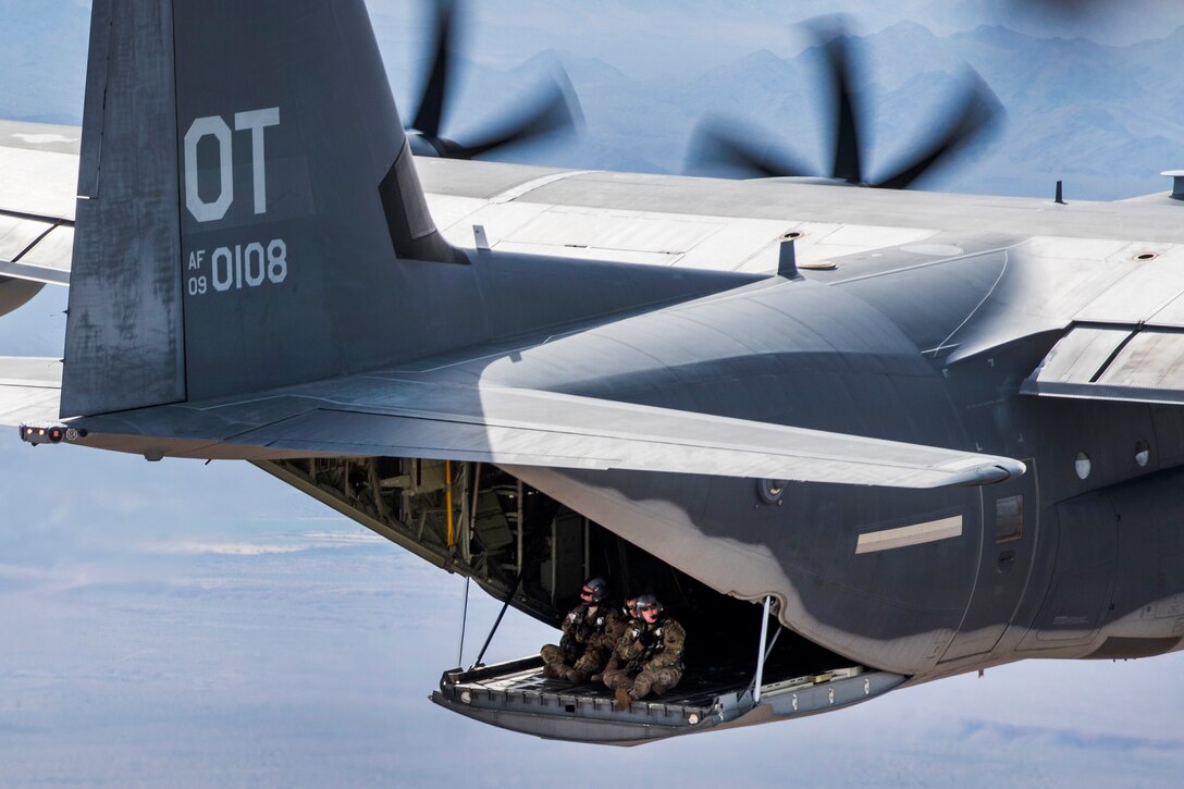 Airmen sit on the ramp of a HC-130J Combat King II cargo aircraft during in-air refueling training mission.