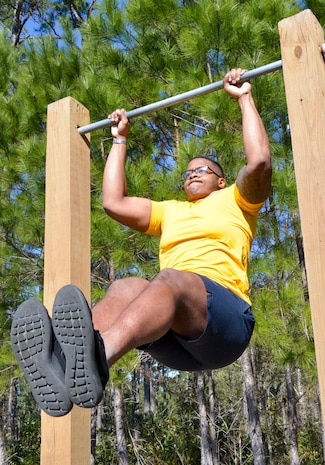 Navy Seaman Nathaniel Mims, a general duty corpsman serving at Naval Health Clinic Charleston, does hanging leg raises during physical fitness training at NHCC. The Moundville, Alabama native lost 120 pounds to join the Navy and is now inspiring others to lose weight and get in shape.
