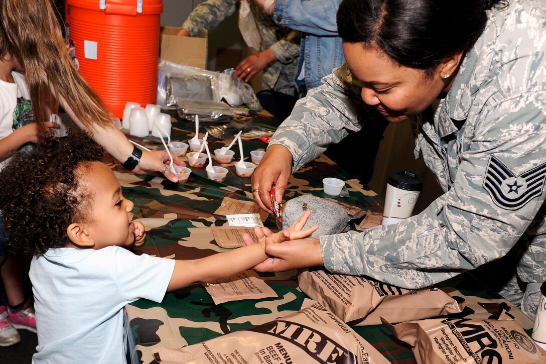 A member of the Air Force places a candy in a child's hand.