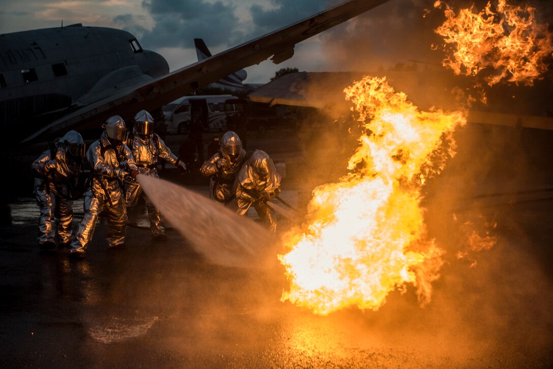 Military firefighters extinguish an aircraft fire during a training exercise.