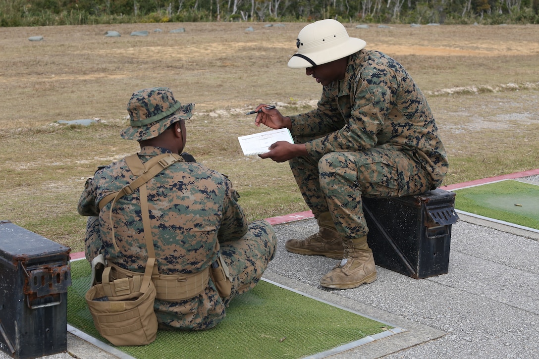 CAMP SCHWAB, OKINAWA, Japan – A range coach gives a Marine advice about their shot grouping on the rifle range Feb. 14 aboard Camp Schwab, Okinawa, Japan.
