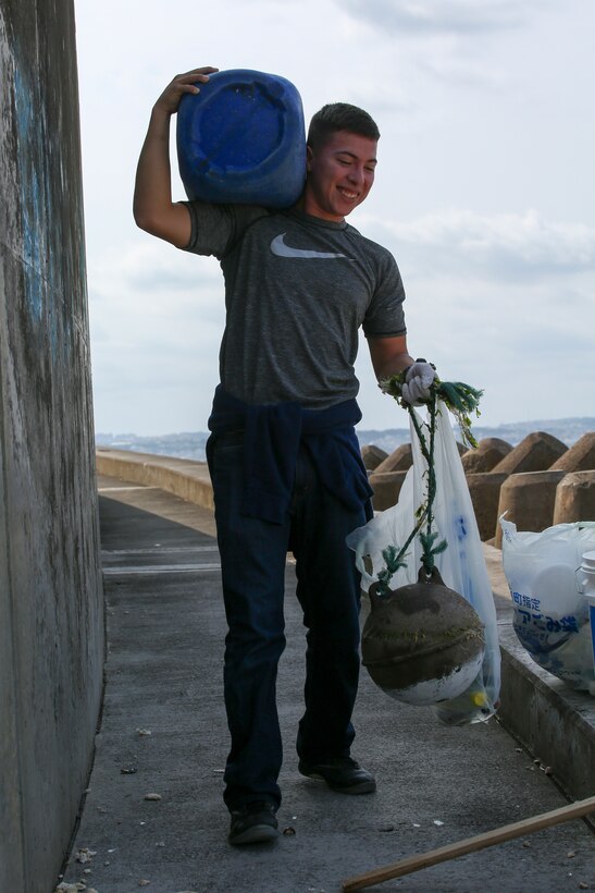 Lance Cpl. Victor Diaz carries the trash he found during a beach cleanup Feb. 24 at Sunabe Seawall, Okinawa, Japan. Twenty-one Marines with the Single Marine Program from Camp Courtney visited the seawall to help clean up debris along the beach. Diaz is a network administrator with Headquarters Battalion, 3rd Marine Division. (U.S. Marine Corps photo by Pfc. Nicole Rogge)