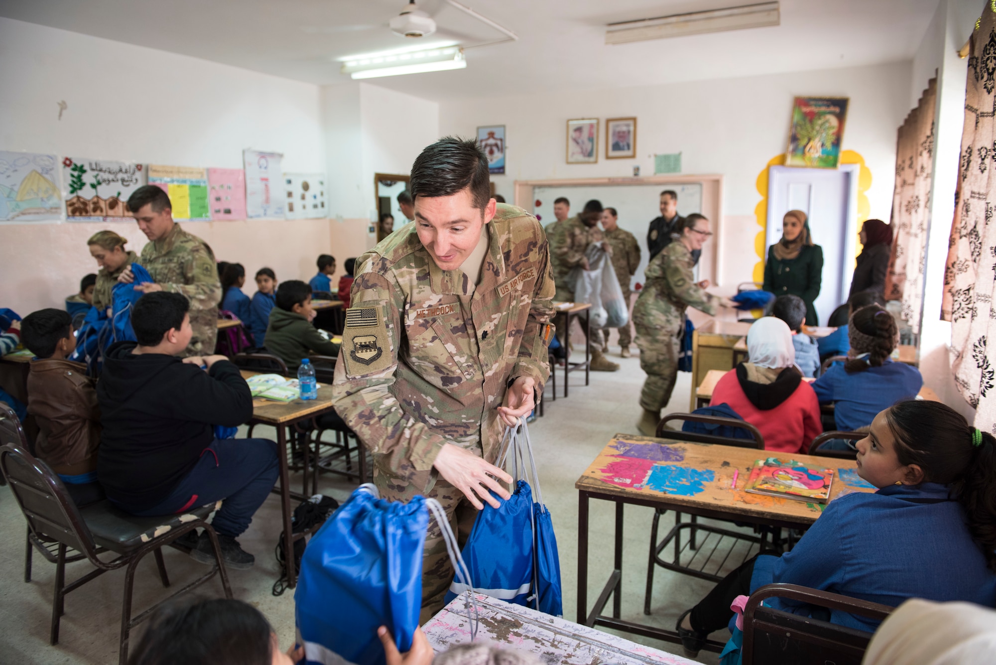 Lt. Col. Michael Hethcock, assigned to the 332d Air Expeditionary Wing, hands out bags filled with school supplies to children during a donation drop-off February 26, 2018, at an undisclosed location. The “Care for Kids” project served as an outlet for service members to make an impact in the local community while they’re in the region supporting Operation Inherent Resolve. (U.S. Air Force photo by Staff Sgt. Joshua Kleinholz)
