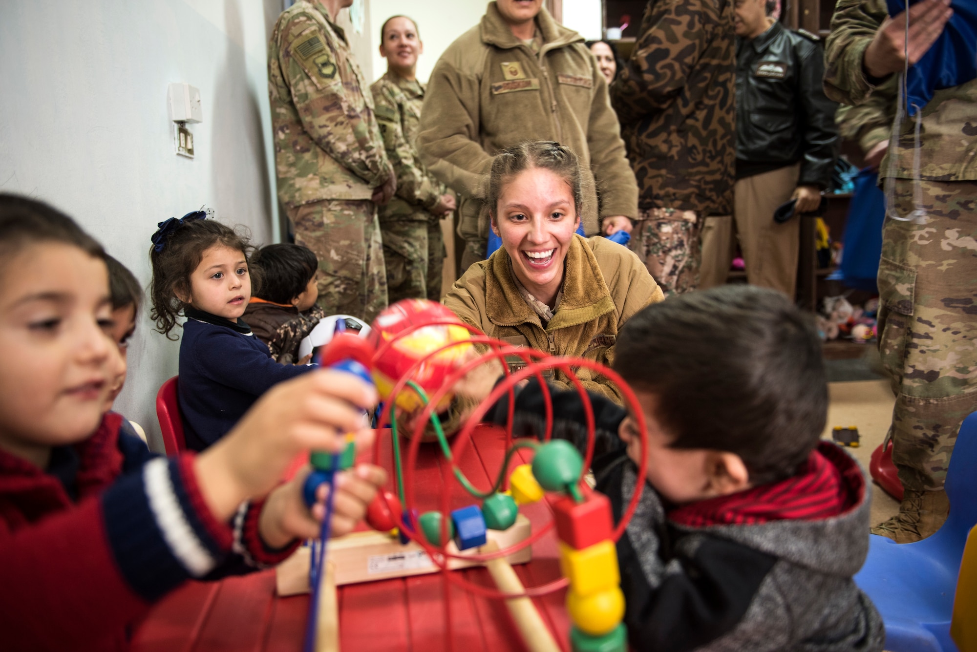 Senior Airman Maria Lopez, assigned to the 332d Expeditionary Security Forces Squadron, plays with children during a donation drop-off February 26, 2018, at an undisclosed location. Service members gathered and delivered supplies in their spare time as they work towards Operation Inherent Resolve objectives. (U.S. Air Force photo by Staff Sgt. Joshua Kleinholz)