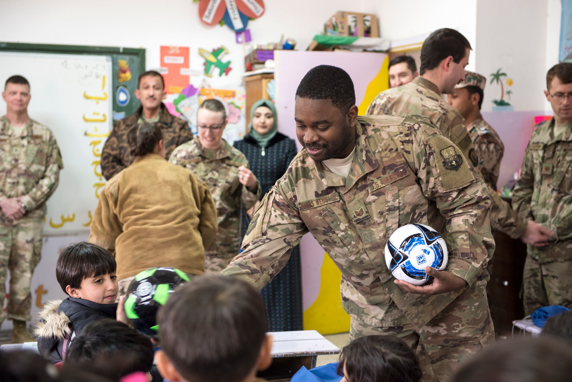 Tech. Sgt. Darren Hinds-Webster, assigned to the 332d Mission Support Group, hands out soccer balls to school children during a donation drop-off February 26, 2018, at an undisclosed location. Service members assigned to the 332d Air Expeditionary Wing had been gathering supplies for more than three months. (U.S. Air Force photo by Staff Sgt. Joshua Kleinholz)