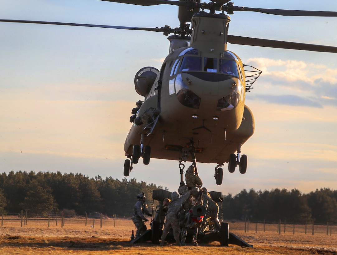 Soldiers sling-load a M777A2 howitzer to a CH-47 Chinook helicopter.