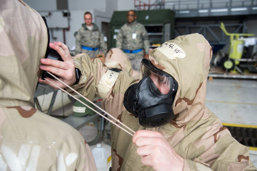 Airman Kyle Wilson, 736th Aircraft Maintenance Squadron aerospace maintenance apprentice, helps a coworker tighten her hood around her gas mask during the 2018 Vengeant Eagle Exercise Feb. 22, 2018, at Dover Air Force Base, Del. All U.S. service members are trained to don and clear their gas mask in nine seconds and must don all their MOPP (Mission Oriented Protective Posture) gear in two minutes or less. (U.S. Air Force photo by Mauricio Campino)