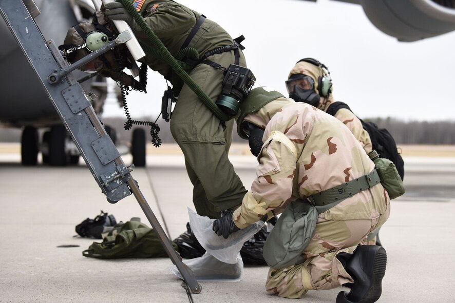 During the 2018 Exercise Vengeant Eagle Feb. 22, 2018, an aircrew member is assisted with donning his boot covers while in MOPP gear. From the flightline, all crew members go directly to the Aircrew Contamination Control area to be decontaminated. (U.S. Air Force photo by Airman 1st Class Zoe M. Wockenfuss)