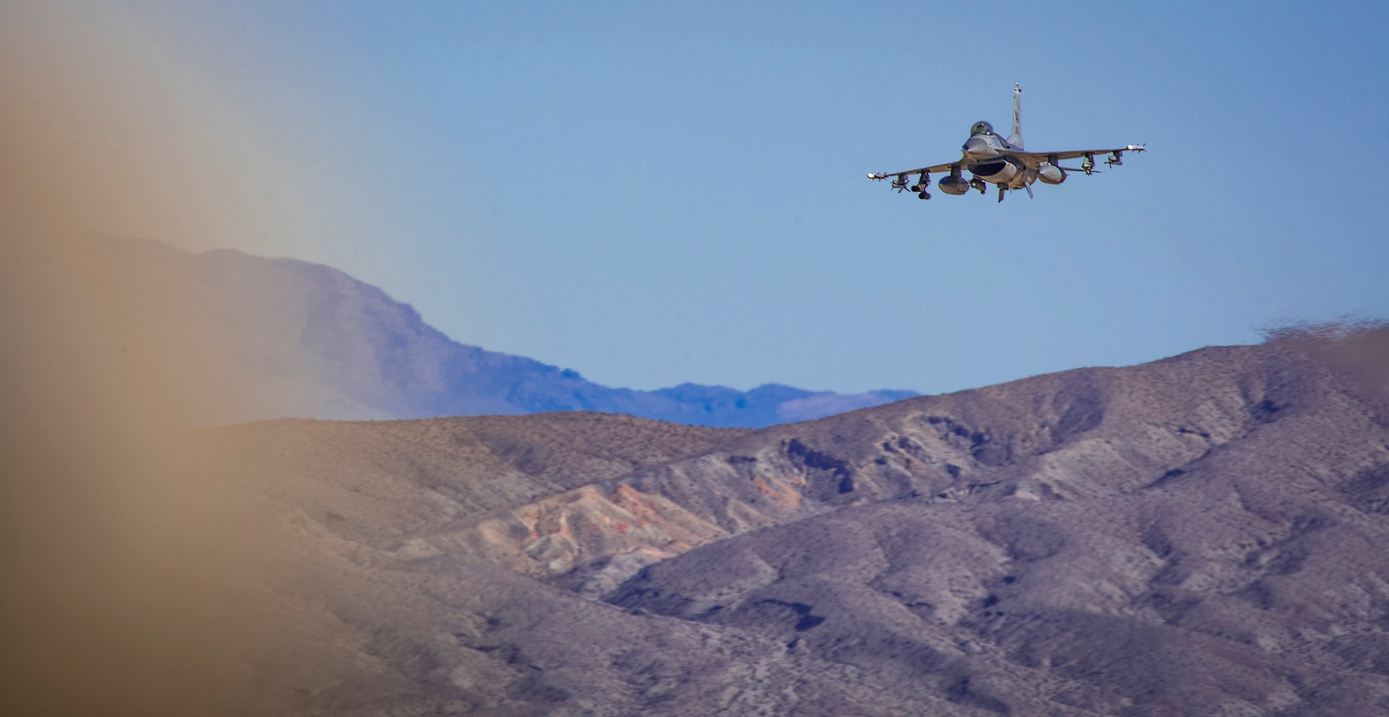 An F-16 Fighting Falcon soars over a mountain ridge in the Mojave Desert during pre-deployment training as part of a National Training Center rotation at Ft. Irwin, Calif., Feb. 20, 2018. During the month-long rotation, 93d Air Ground Operations Wing units embedded with approximately 4,000 soldiers in the largest force-on-force live-fire exercise in the world. The 93d AGOW provided tactical air control party support to enhance interoperability for major combat operations downrange. (U.S. Air Force photo by Senior Airman Greg Nash)
