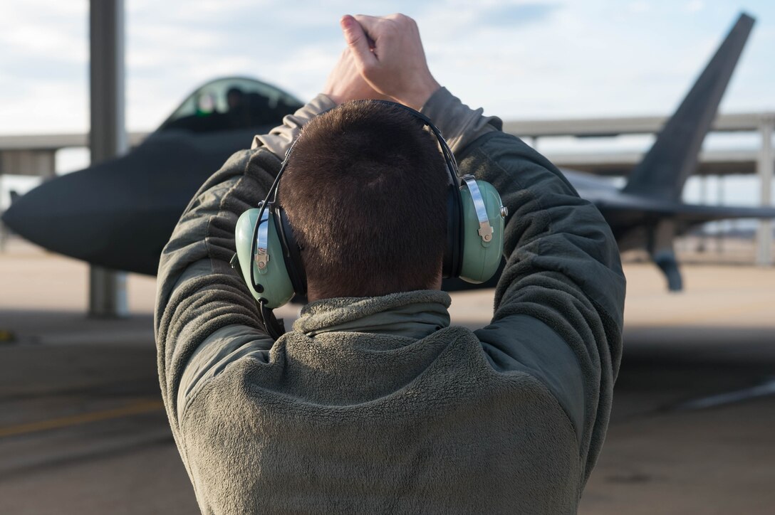 U.S. Air Force Senior Airman Preston Reed, 1st Aircraft Maintenance Squadron, 94th Tactical Aircraft Maintenance Squadron crew chief, guides an F-22A Raptor into its parking spot at Joint Base Langley-Eustis, Virginia, Feb. 14, 2017. Reed performs post-flight inspections of the hydraulic systems, landing gears and electrical systems for any damage that needs replaced. (U.S. Air Force photo by Senior Airman Derek Seifert)