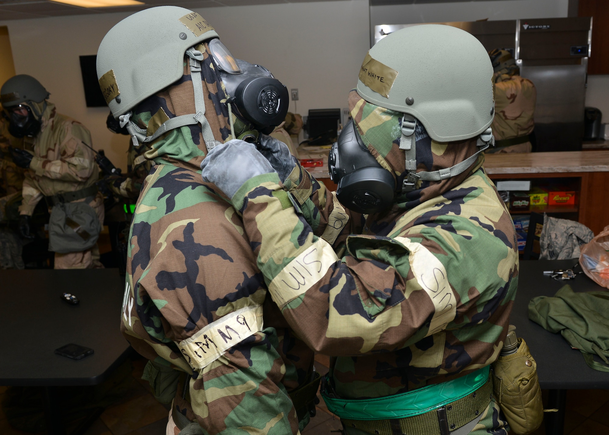 U.S. Air Force Airmen inspect each other after putting on mission-oriented protective posture gear at Joint Base Langley- Eustis, Virginia, Feb. 26, 2018.