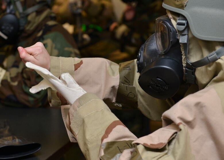 A U.S. Air Force Airman removes her gloves after participating in the Chemical Attack Survival Familiarization exercise on Joint Base Langley-Eustis, Virginia, Feb. 26, 2018.