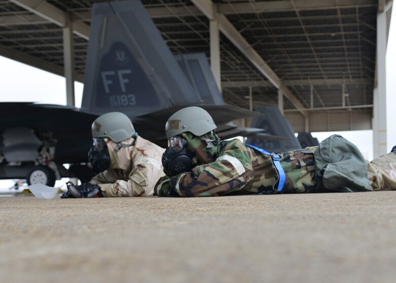U.S. Air Force Airmen lay on the ground after putting on Mission Oriented Protective Posture gear at Joint Base Langley- Eustis, Virginia, Feb. 26, 2018.
