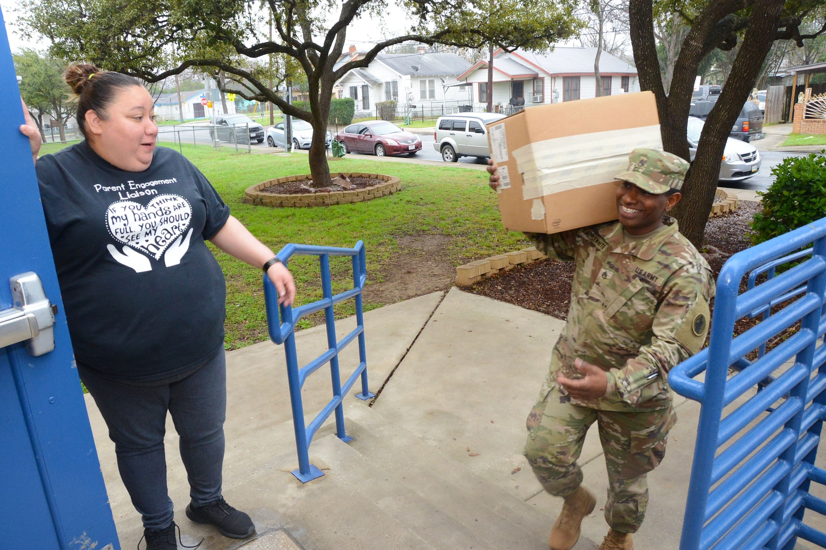 Staff Sgt. Darrell Applewhite (right), Headquarters and Headquarters Battalion, U.S. Army South, is greeted by Julia Losoya, the Parent and Family Liaison atBooker T. Washington Elementary School, as he carries in one of many boxes of winter coats into the school Feb. 22. The school and unit are partnered through the Adopt-a-School program. Units on Fort Sam Houston are partnered with schools with the Northeast Independent School District, the San Antonio Independent School District and the Fort Sam Houston Independent School District.