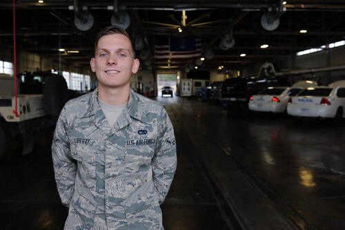 Man poses for photo inside maintenance bay of government cars
