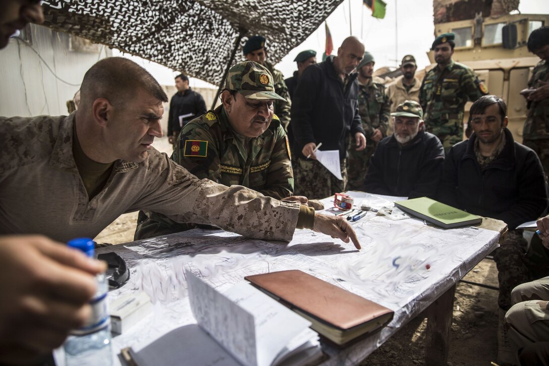 A Marine leader points to a map as he talks with Afghan military leaders.