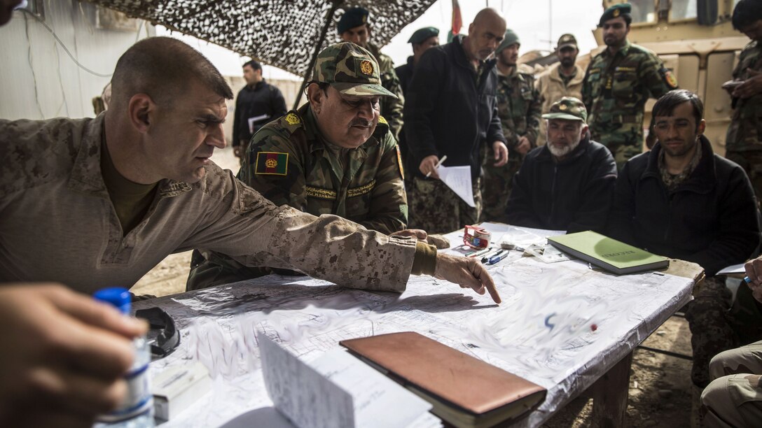 A Marine leader points to a map as he talks with Afghan military leaders.
