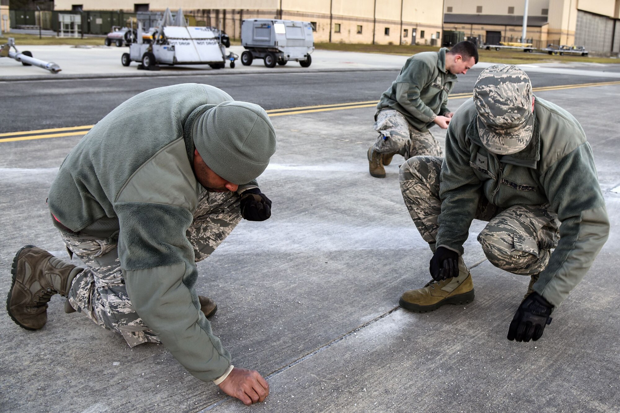 Team Moody Airmen grab debris off of the flight line during a foreign object debris (FOD) walk, Jan. 2, 2018, at Moody Air Force Base, Ga. The FOD walk was performed following the winter holidays to remove any debris that could potentially cause damage to aircraft or vehicles. (U.S. Air Force photo by Airman Eugene Oliver)