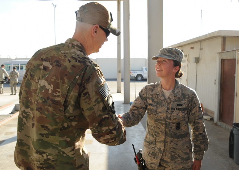 Chief Master Sgt. Ronald Anderson, command chief master sergeant of the Air National Guard coins Airman 1st Class Rachel Smith, 380th Expeditionary Security Forces Squadron, installation entry controller, during his visit to Al Dhafra Air Base, United Arab Emirates Dec. 26, 2017. Smith is deployed from the 166th Airlift Wing, New Castle Air National Guard Base, Delaware.