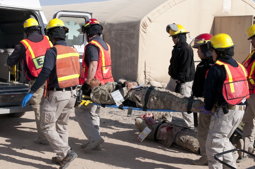 First responders load a mock patient into a vehicle.