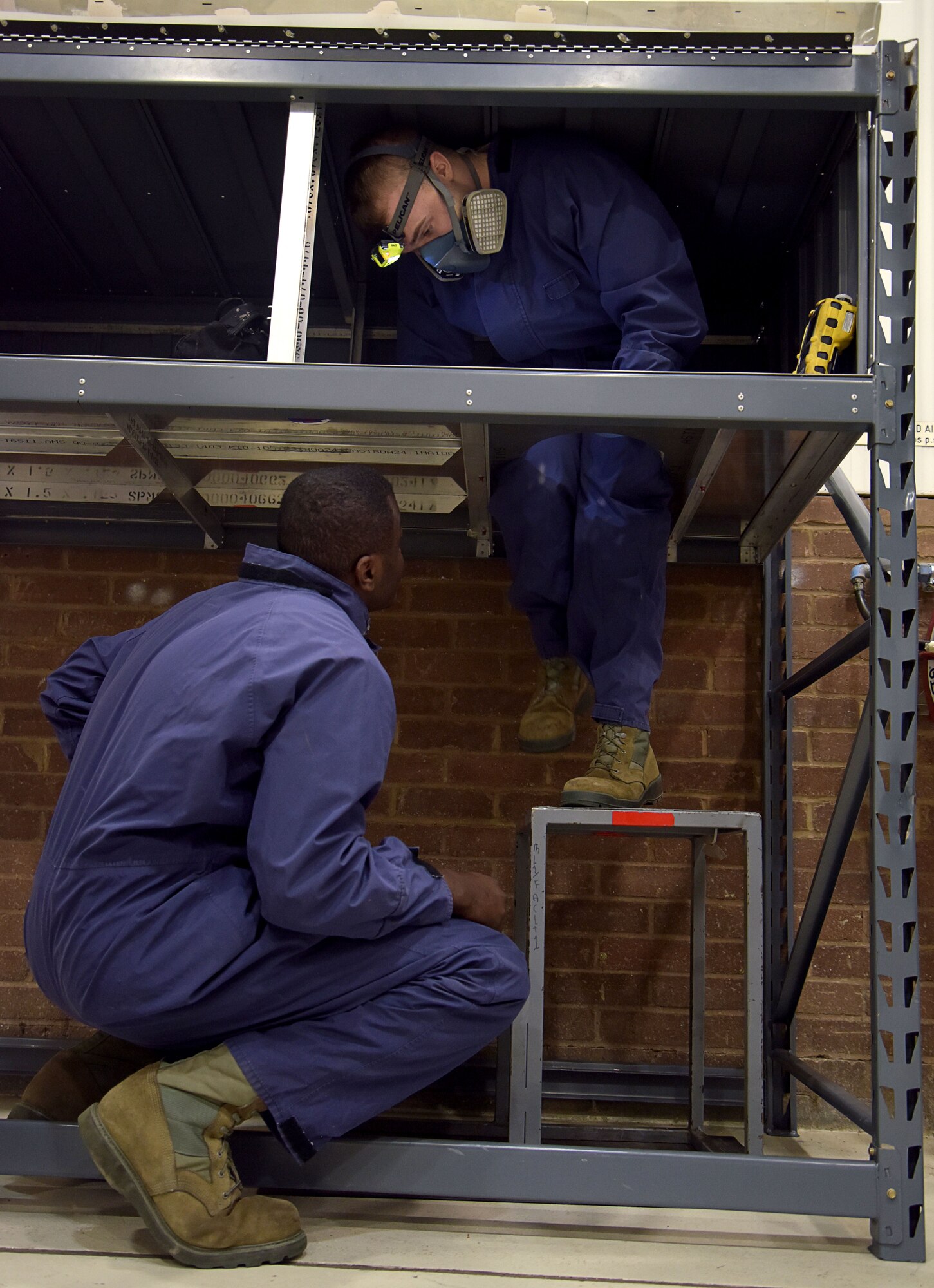 U.S. Air Force Staff Sgt. Gerry Donald, 100th Maintenance Squadron aircraft fuel systems craftsman, bottom, oversees Airman Shawn Bragg, 100th MXS aircraft fuel systems apprentice, entering the confined space trainer Dec. 15, 2017 on RAF Mildenhall, England. A team, involving multiple sections within the 100th MXS, designed and constructed the trainer to create a safe and control training environment. The trainer better prepares Airmen when entering fuel tanks on an aircraft. (U.S. Air Force photo by Senior Airman Justine Rho)