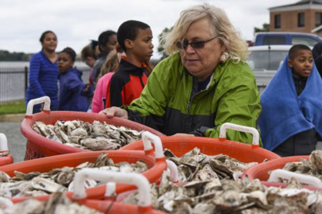 A woman holds a bucket of oysters.
