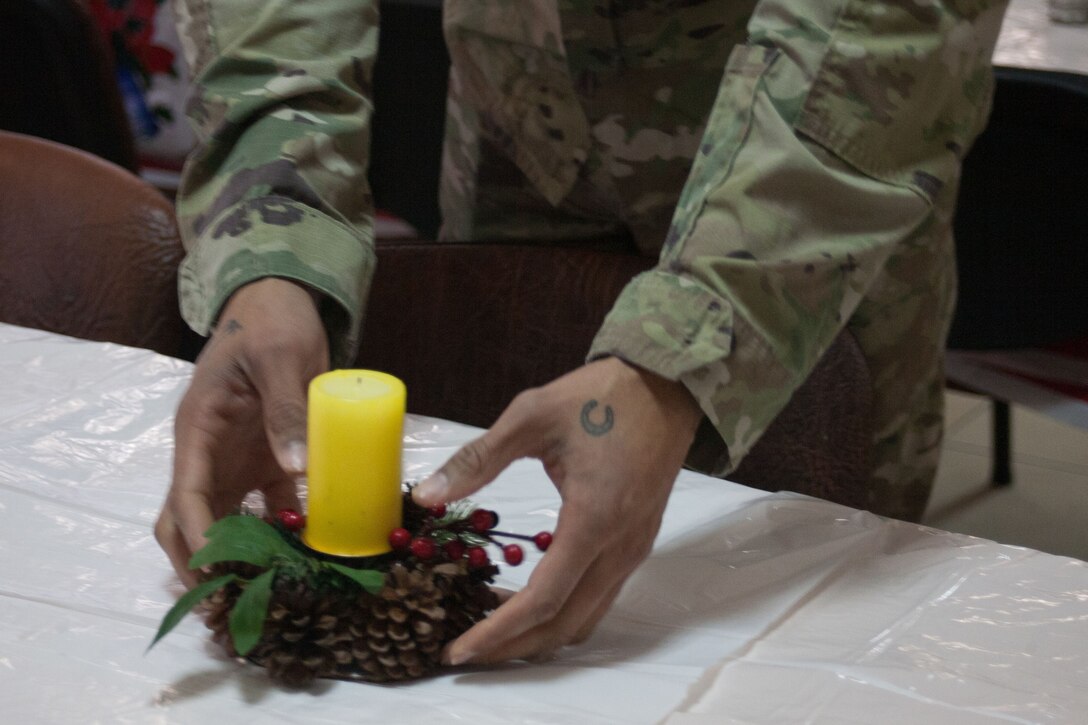 A soldier places a small candle centerpiece on a table.
