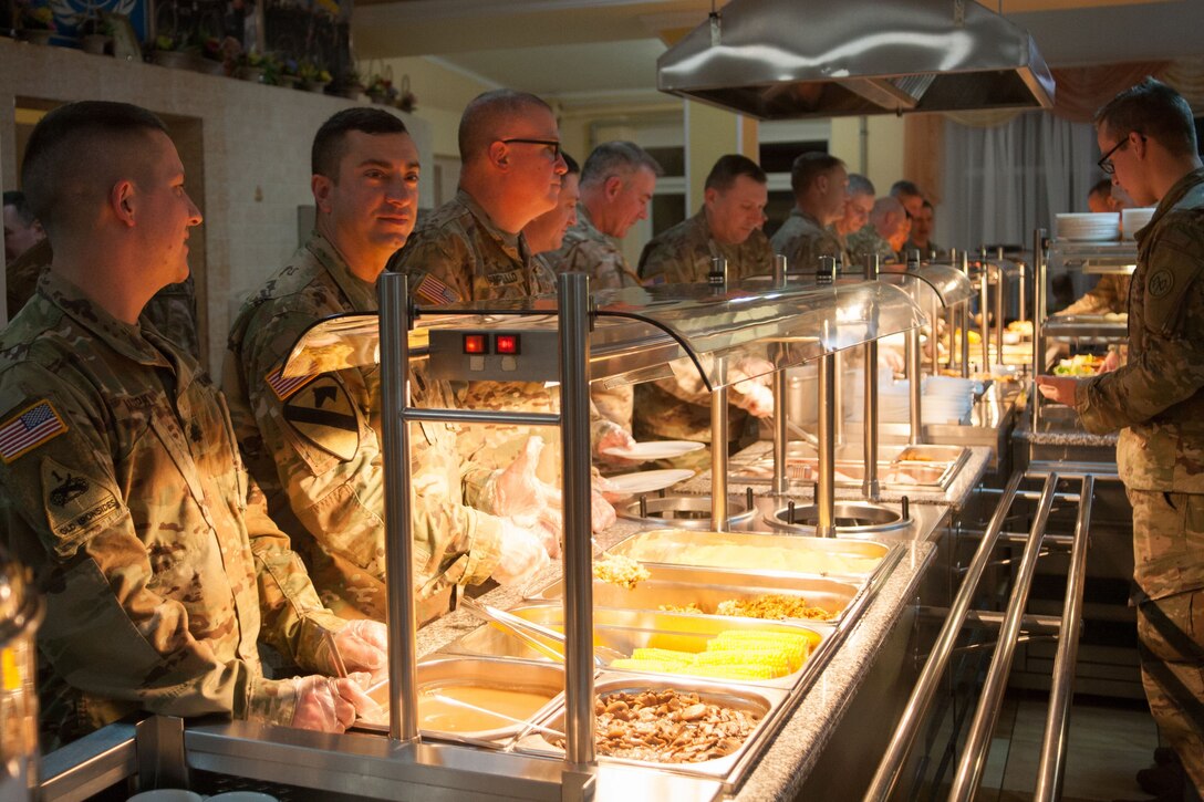 Soldiers form two lines around a food buffet.