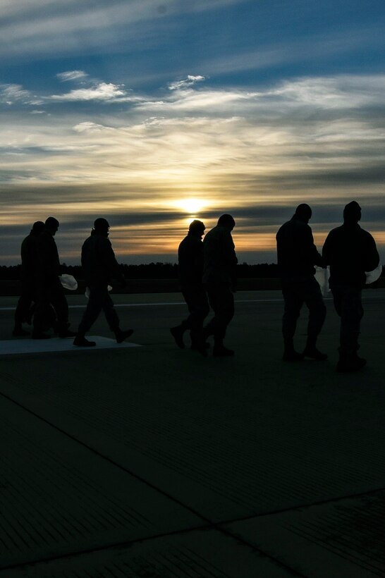 A group of airmen inspect a flight line at twilight.
