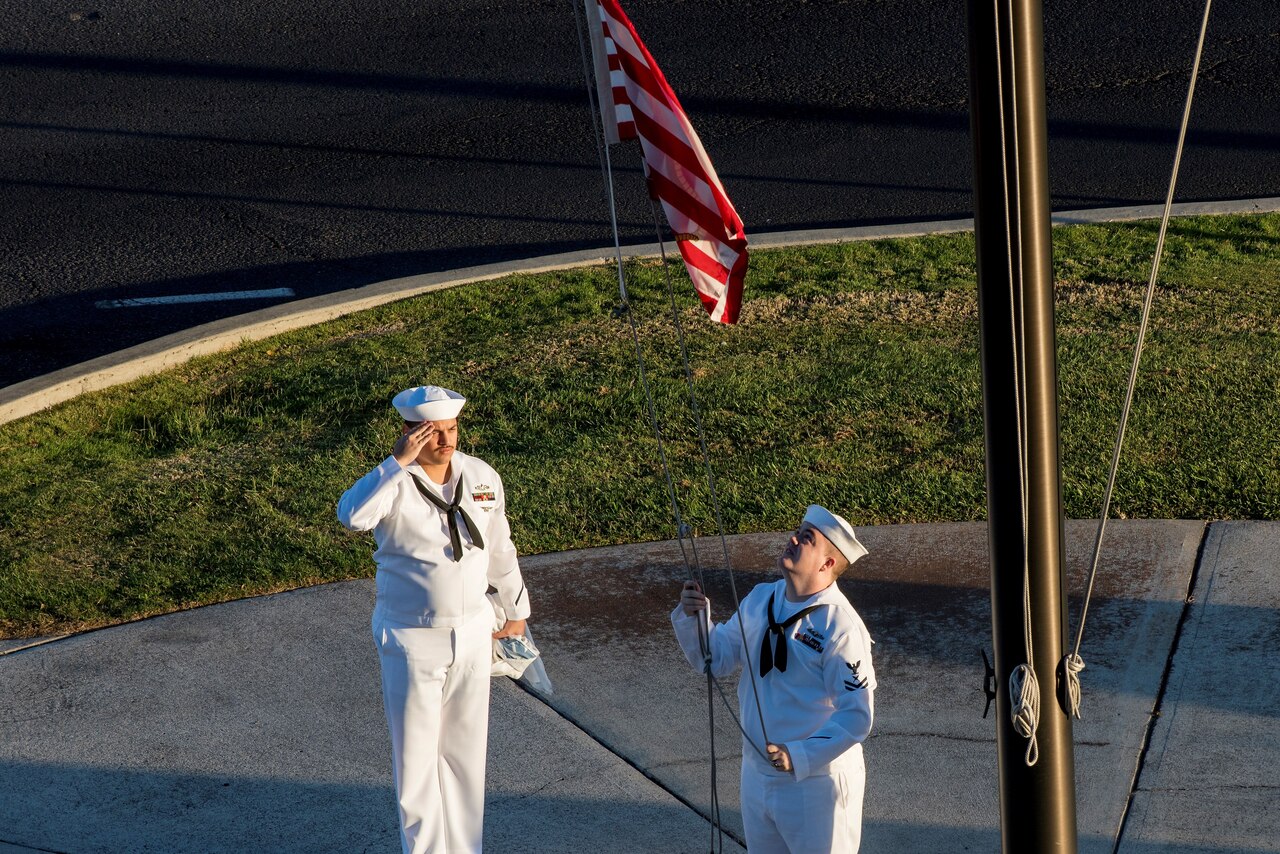 Navy Petty Officer 2nd Class Gerado Taddei, left, and Petty Officer 2nd Class Andrew Thompson fly the "First Navy Jack" to start the New Year on Joint Base Pearl Harbor-Hickam, Hawaii, Jan. 1, 2018.
