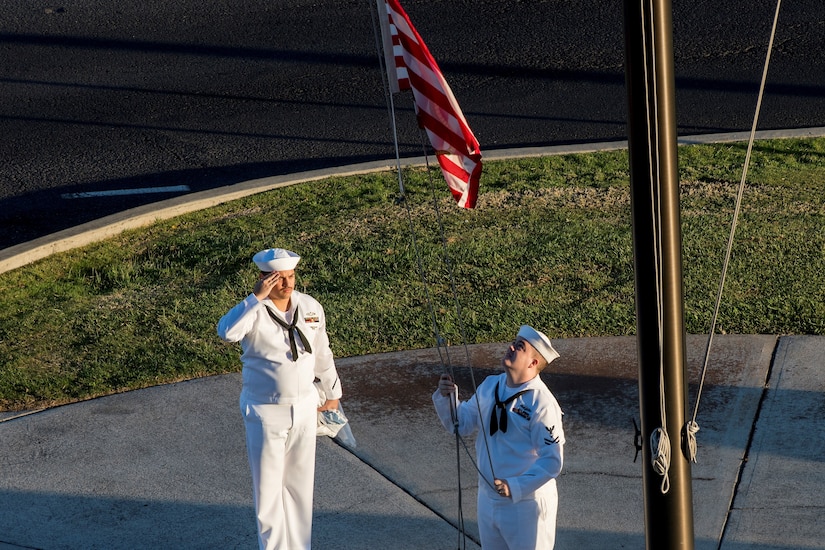 Navy Petty Officer 2nd Class Gerado Taddei, left, and Petty Officer 2nd Class Andrew Thompson fly the "First Navy Jack" to start the New Year on Joint Base Pearl Harbor-Hickam, Hawaii, Jan. 1, 2018.