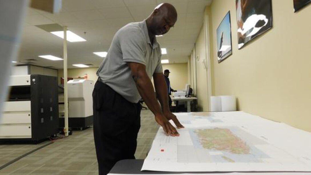 DLA Aviation employees stands over map