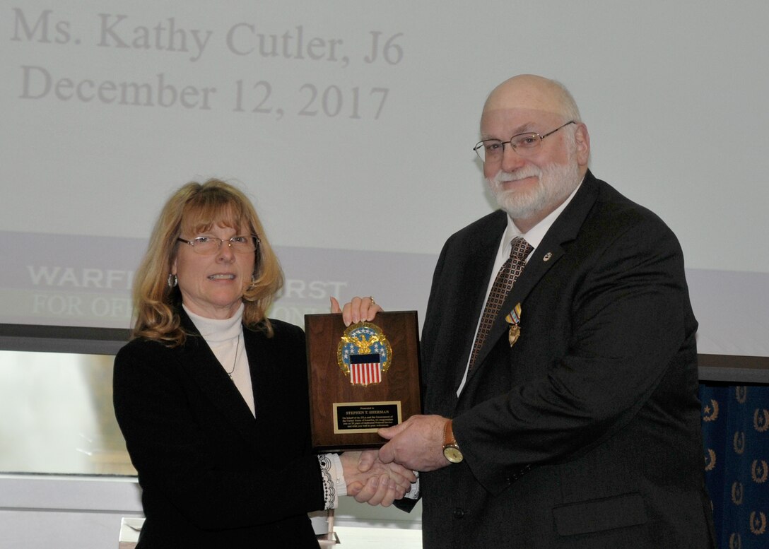Steve Sherman receives his retirement plaque from DLA Information Operations Chief Information Officer Kathy Cutler Dec. 12, after 38 years of federal service.