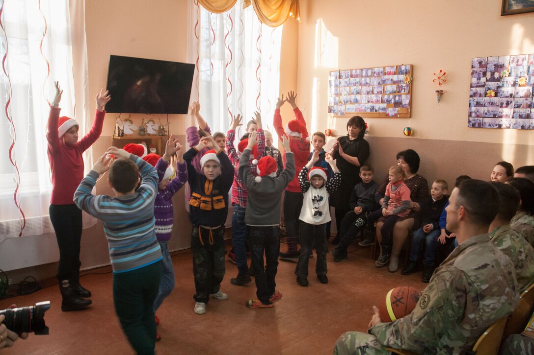 Children sing and dance for visiting soldiers.