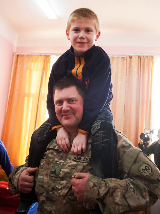 A soldier holds a child on his shoulders.