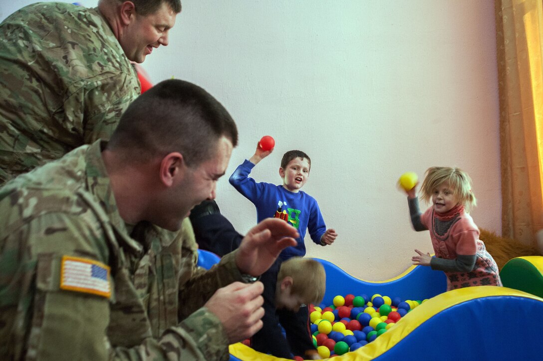 Soldiers about to get hit by toy balls being thrown by children.