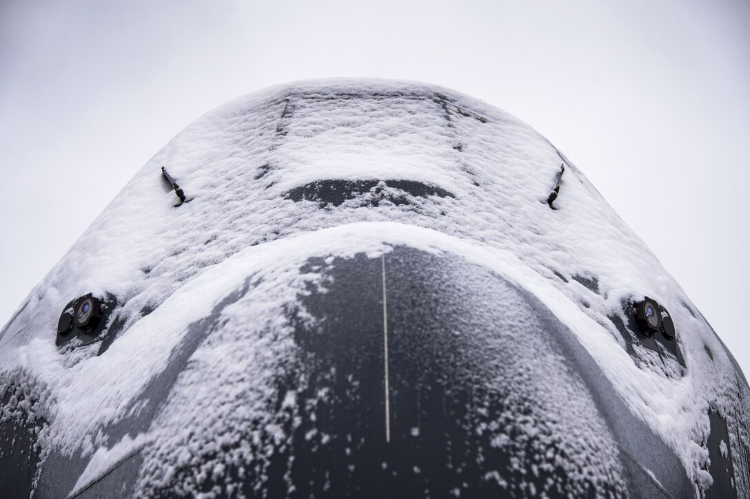Snow covers an aircraft's nose and windshield.