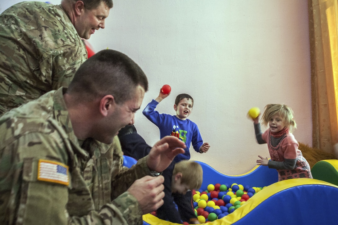 Soldiers play with children during a visit to an orphanage.