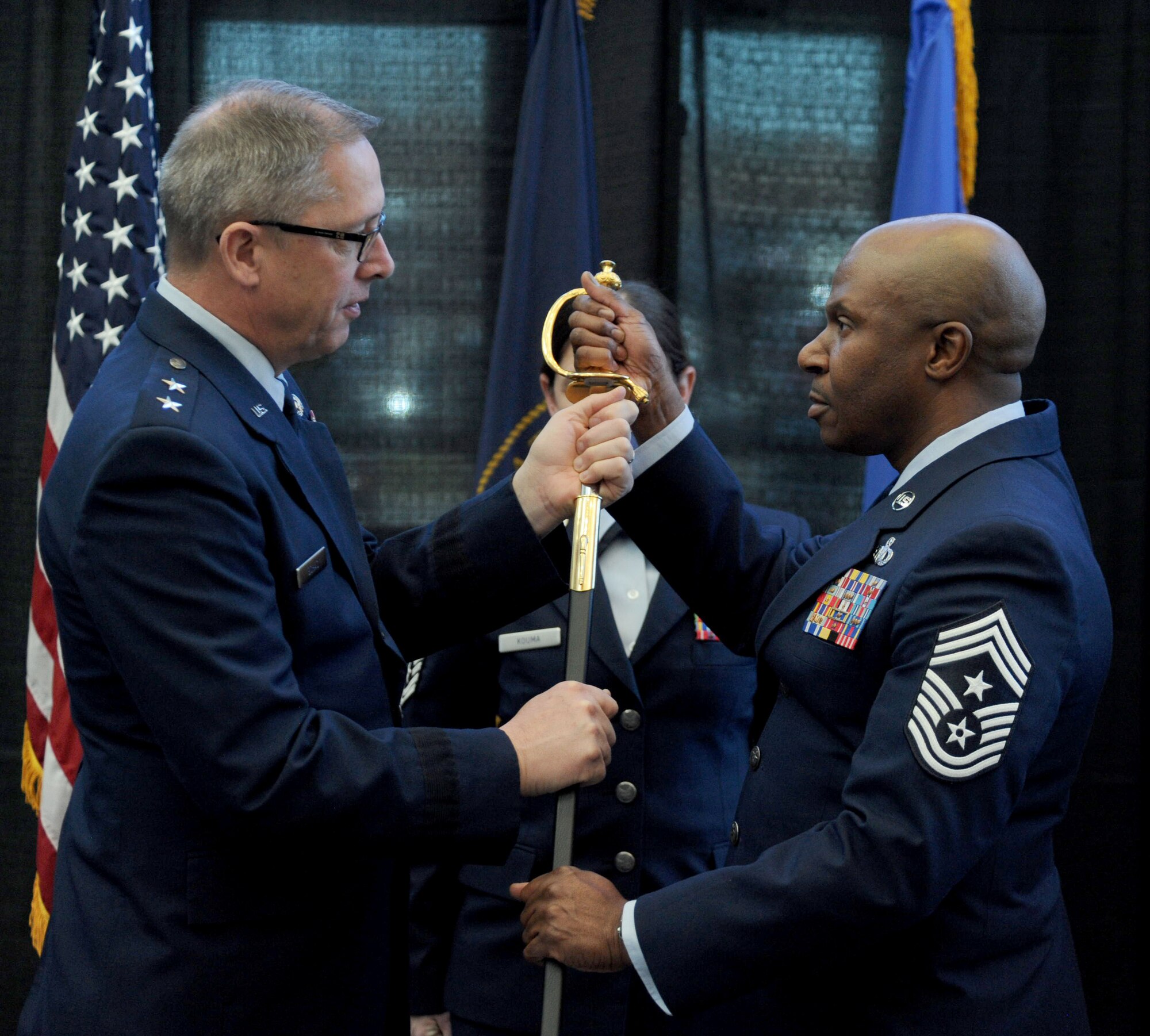 Chief Master Sgt. Tyrone Bingham receives a sword, symbolizing the transfer of responsibility from the outgoing senior enlisted leader to the incoming, from Maj. Gen. Daryl Bohac, Nebraska adjutant general during a formal ceremony held Dec. 2, 2016 at the Nebraska Joint Force Headquarters in Lincoln, Nebraska.
