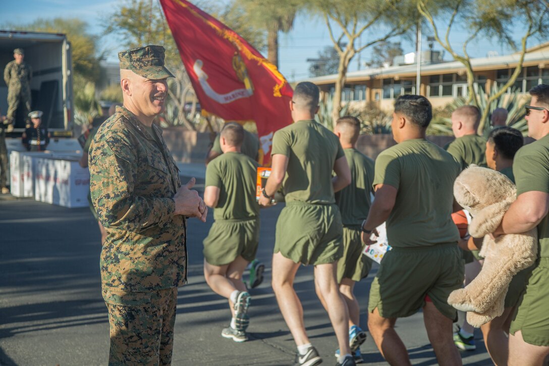 Maj. Gen. William F. Mullen III, Commanding General, Marine Corps Air Ground Combat Center, Twentynine Palms, Calif.,  watches as Marines with Marine Corps Communication-Electronics School run past during the annual Toys-for-Tots Run aboard the base, Dec. 18, 2017. Marines ran with toys and dropped them off in front of the Commanding General’s building. (U.S. Marine Corps photo by Lance Cpl. Preston L. Morris)