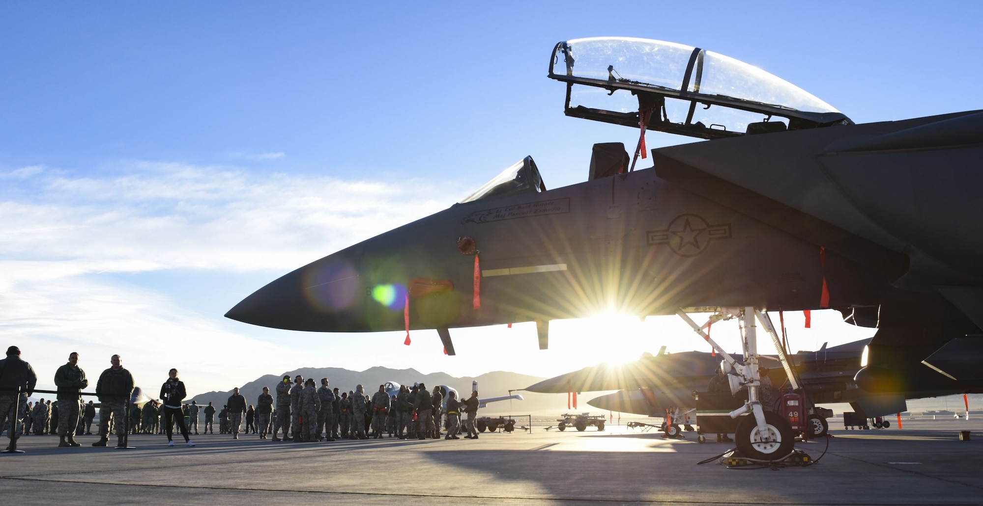 Airmen gather around an F-15C Eagle and an F-16 Fighting Falcon fighter jets after the quarterly load crew competition at Nellis Air Force Base, Nev., Jan. 5, 2018. All teams inspected, loaded and secured two bombs and one missile to their aircraft within an hour. (U.S. Air Force photo by Airman 1st Class Andrew D. Sarver/Released)
