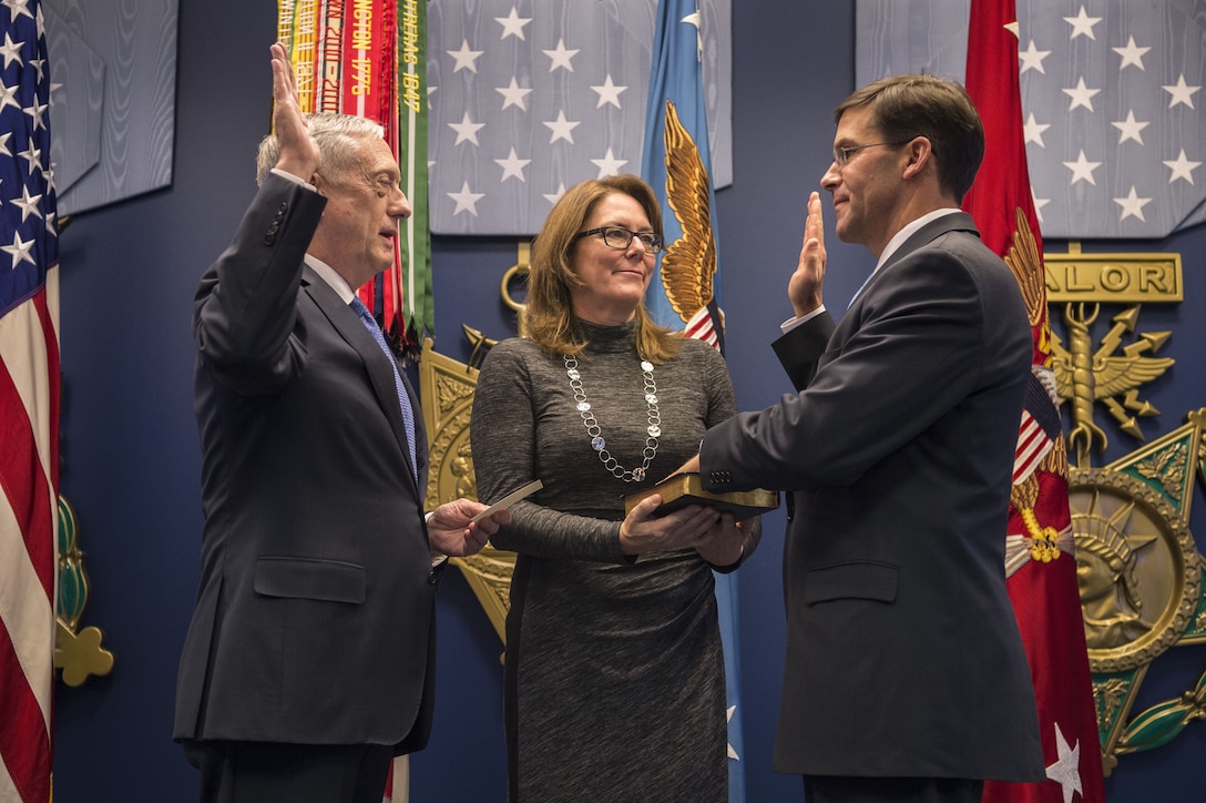 Defense Secretary James N. Mattis stands across from a man being sworn into office.