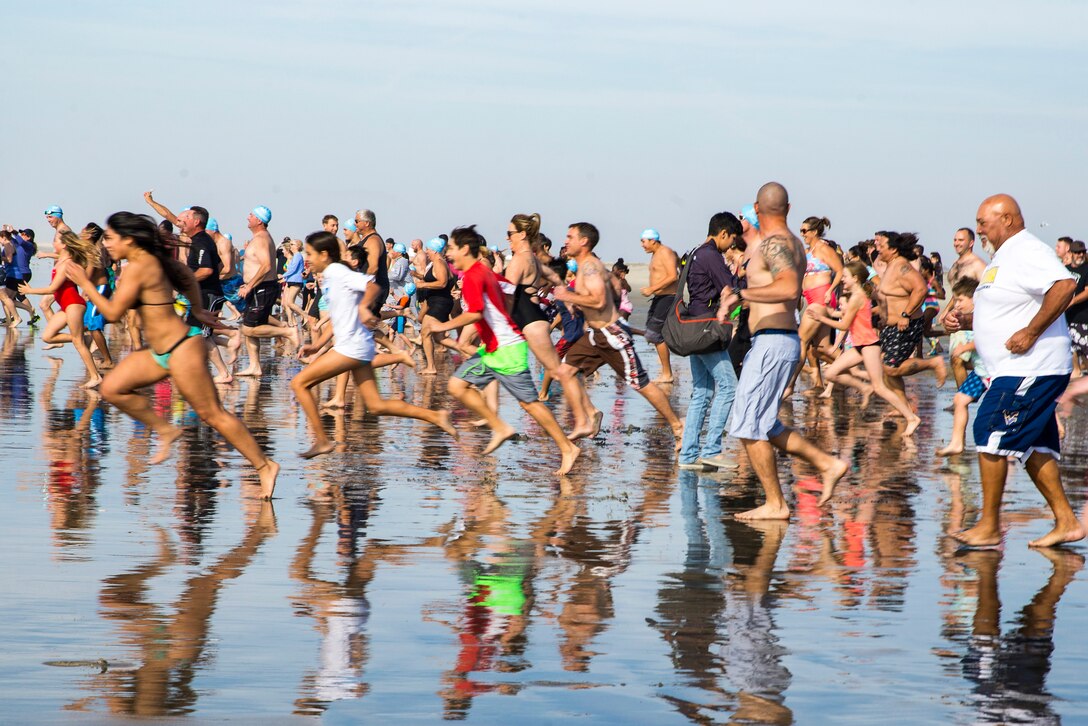 People run on a beach.